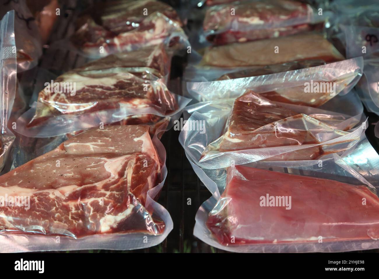Rindersteaks werden in einem speziellen Kühlschrank aufbewahrt, bevor sie gekocht werden. Steaks in luftdichten Verpackungen im Kühlschrank. Reifung von Steaks vor dem Kochen. Stockfoto