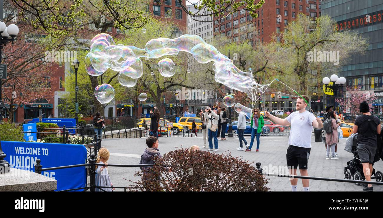 New York, USA - 15. April 2017: Ein Straßenkünstler schafft große Seifenblasen auf dem Union Square, die Zuschauer in ihren Bann ziehen. Stockfoto