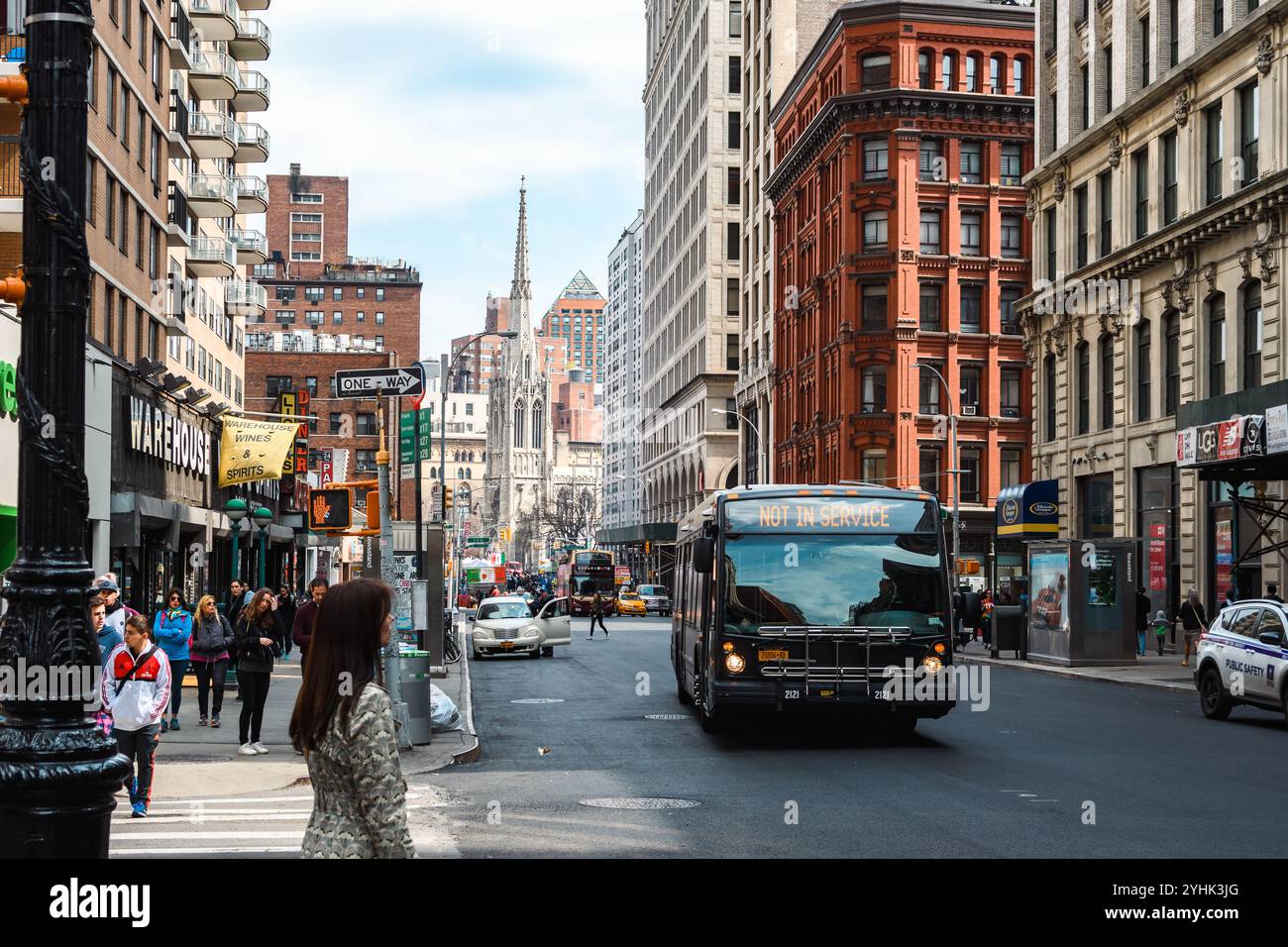 New York, USA - 15. April 2017: Eine geschäftige Straßenszene mit Fußgängern, einem Bus und einer berühmten Architektur im Hintergrund. Stockfoto