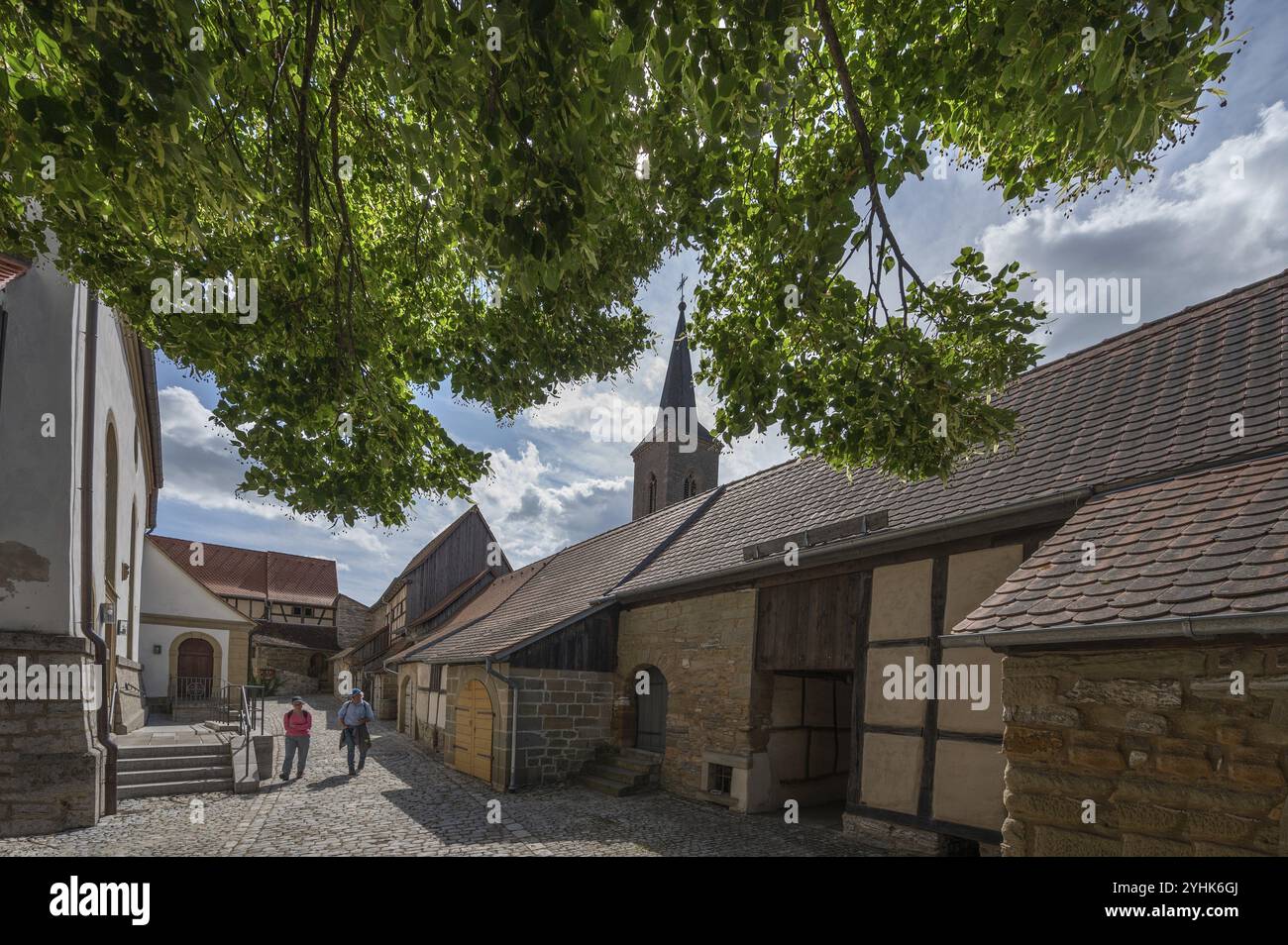 Innenhof mit ehemaligen sogenannten Kirchenarkaden, Scheunen in der historischen Festungskirche, Kirche St. Johannes des Täufers hinten, Huettenheim, Stockfoto