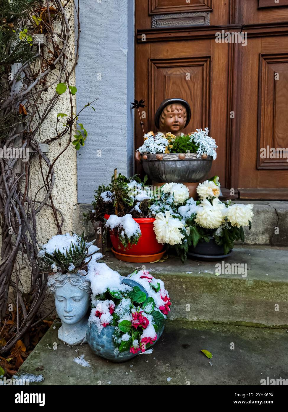 Weihnachtsdekoration des Hauseingangs. Figuren und frische Blumen in Töpfen, besprüht mit frischem weißem Schnee. Stockfoto