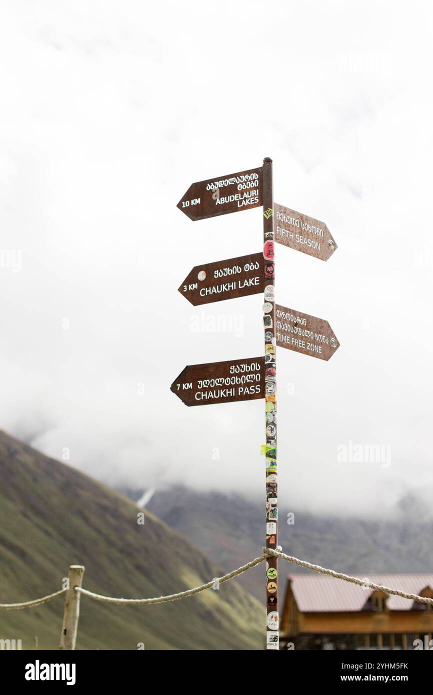 Dieses vertikal ausgerichtete Foto zeigt einen verwitterten Wegweiser in den malerischen Bergen von Georgien, der während der Herbstse aufgenommen wurde Stockfoto