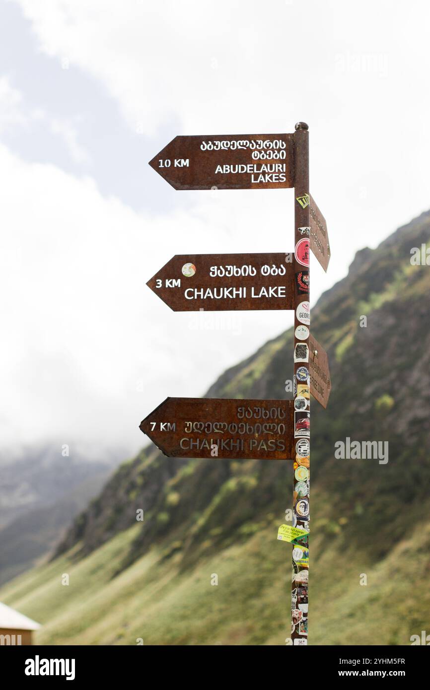 Dieses vertikal ausgerichtete Foto zeigt einen rostfarbenen Wegweiser in den zerklüfteten Bergen Georgiens im Herbst. Der Wegweiser wird angezeigt Stockfoto