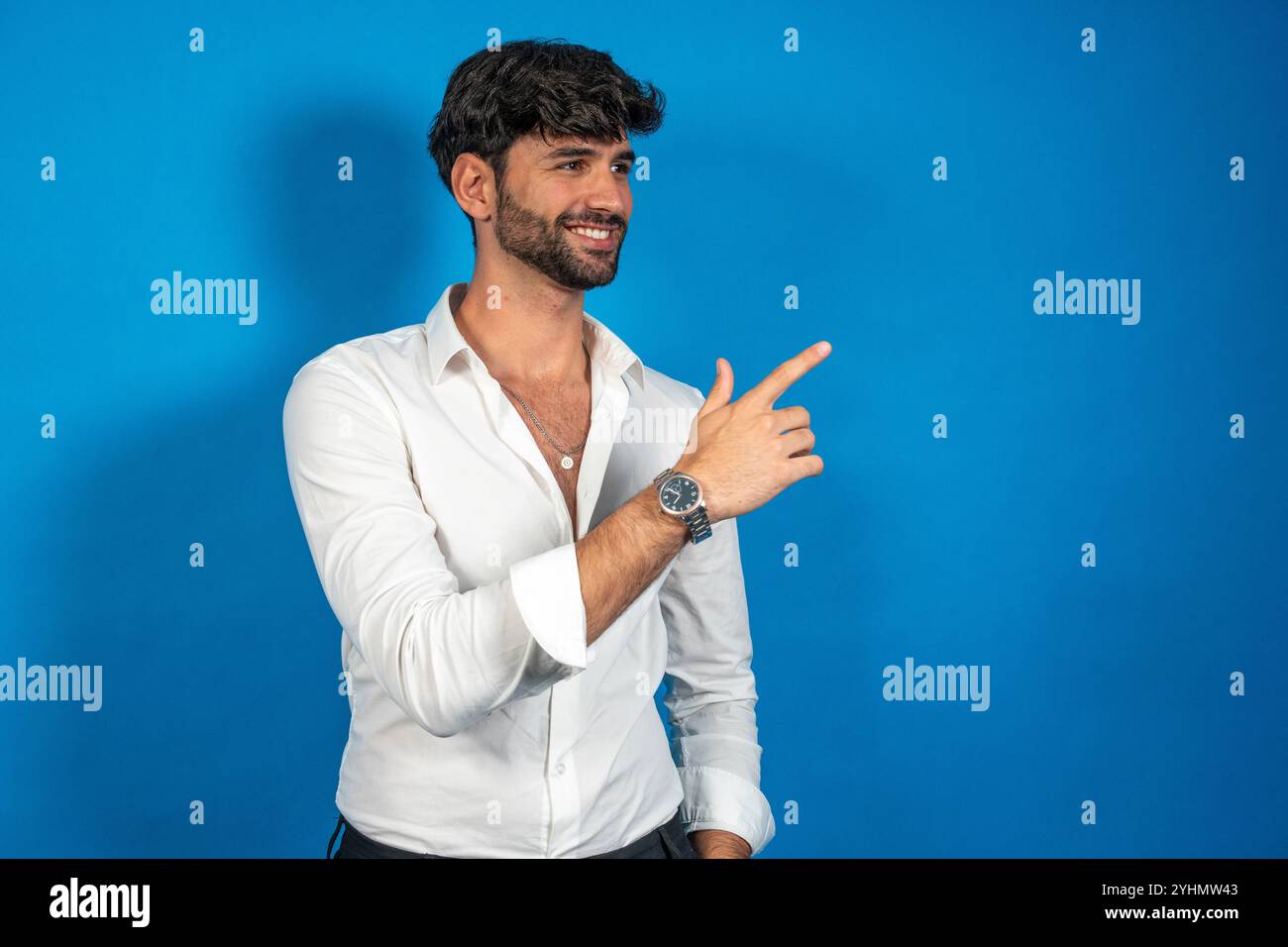 Junger Geschäftsmann, der mit dem Finger zeigt, was Interessantes auf blauem Hintergrund zeigt Stockfoto