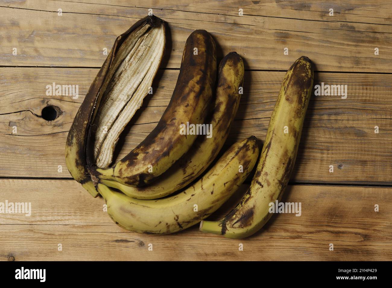 Bild von vier braunen Bananen auf hölzernem Hintergrund. Stockfoto