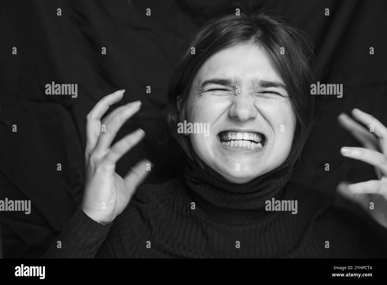 Ein dramatisches Schwarz-weiß-Porträt einer schreienden Frau mit einem Ausdruck von Wut und Angst. Innerer Aufruhr, Störung und Depression Stockfoto