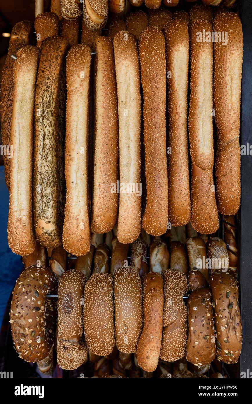 Verschiedene frisch gebackene Bagels und runde Brote hängen auf einem Metallregal in einer Bäckerei in Tel Aviv, Israel. Stockfoto