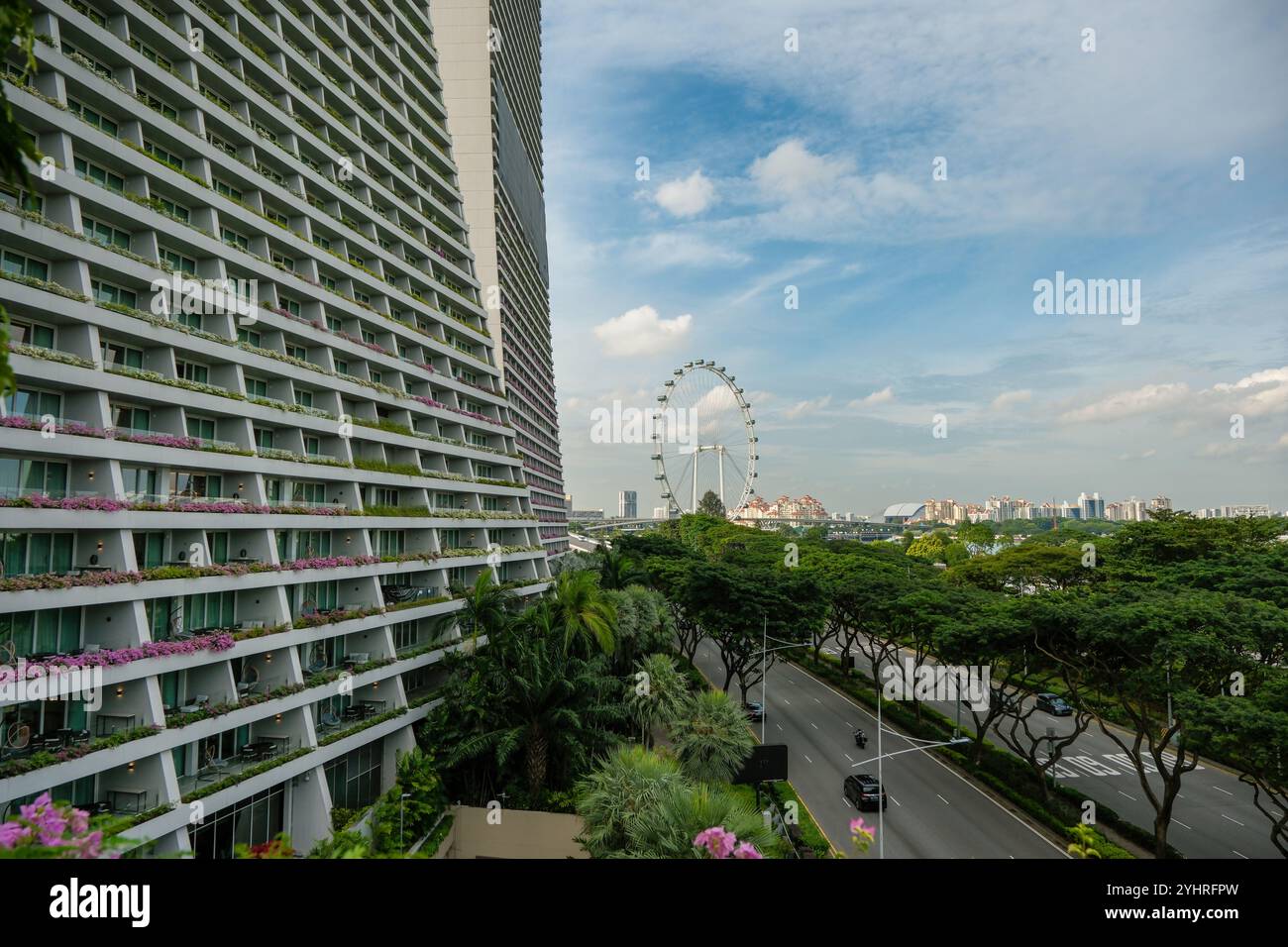 Ein Blick über Singapur mit einem Teil des Marina Bay Sands Hotel Balkons im Vordergrund mit Blick auf die Singapore Flyer Attraktion. Stockfoto