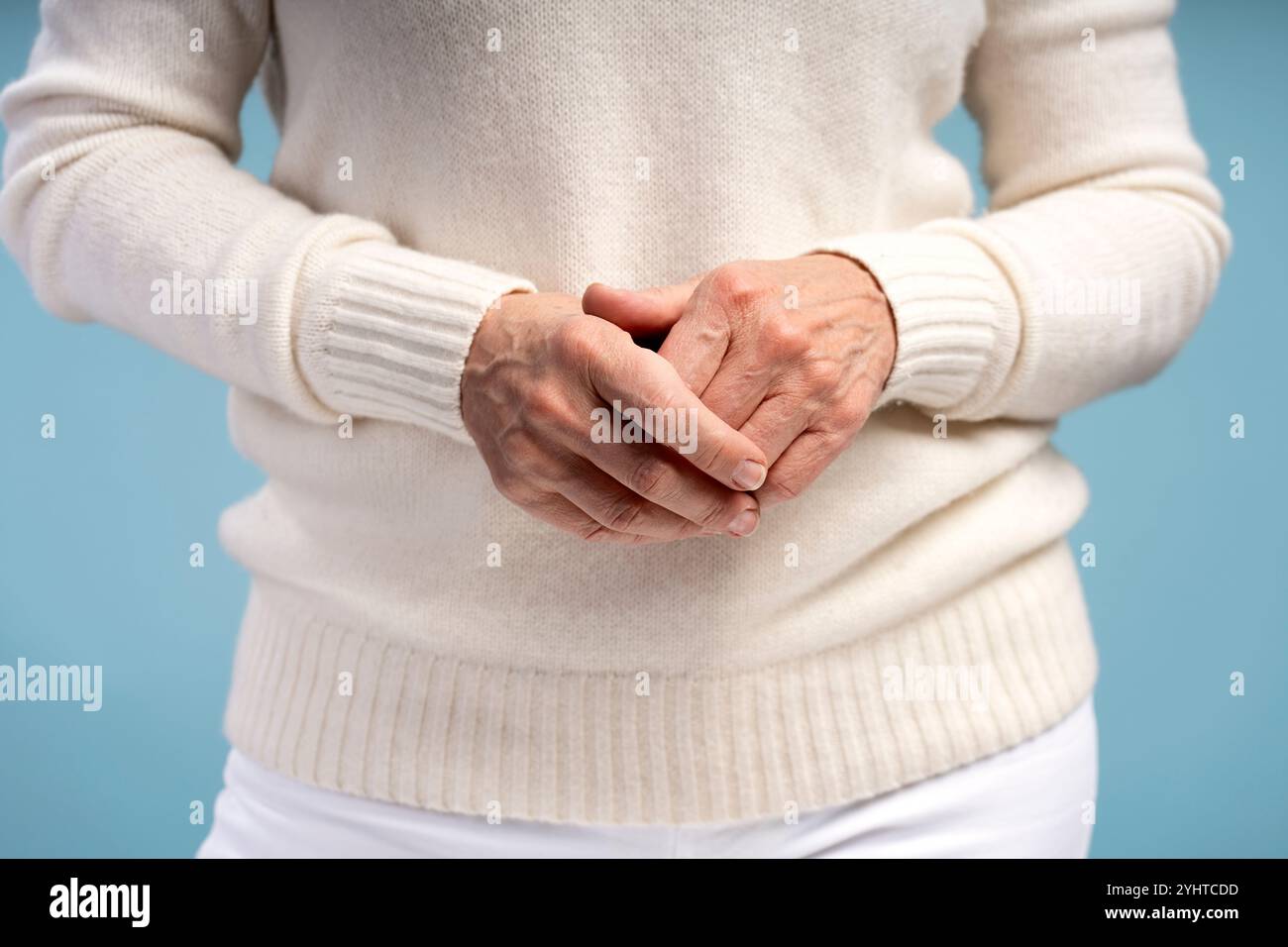 Nahaufnahme, pensionierte Frau in lässiger Kleidung, selektiver Fokus auf die Hände, isoliert auf blauem Hintergrund. Werbekonzept Stockfoto