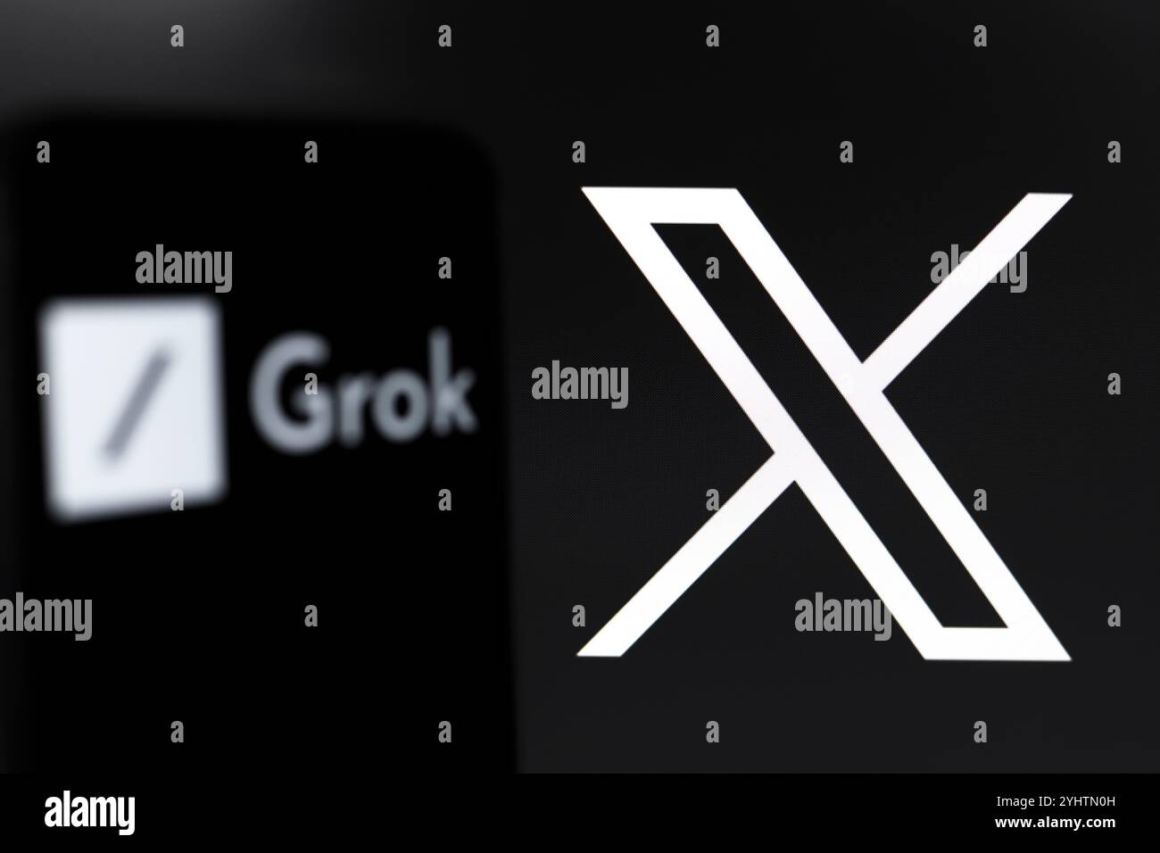 Das Grok-Logo wird auf dem Bildschirm eines Smartphones und im Hintergrund, das Logo des sozialen Netzwerks X (ehemals Twitter) auf dem Computer sc angezeigt Stockfoto
