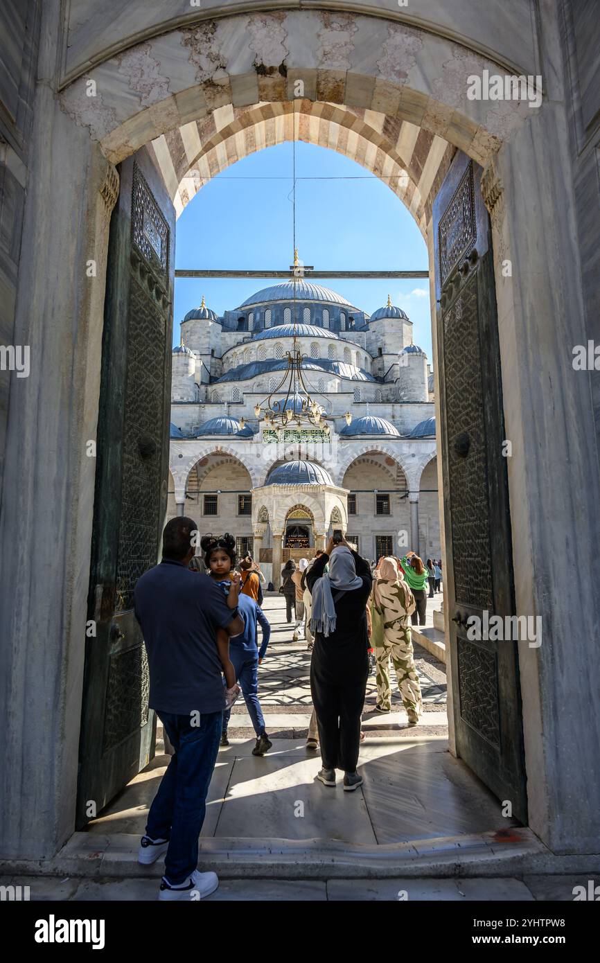 24/10/2024. Die Blaue Moschee, Istanbul, Türkei. Besucher betreten und verlassen den Innenhof. Die Blaue Moschee, offiziell Sultan Ahmed Moschee (türkisch Sultan Ahmet Camii), ist eine historische Moschee aus der osmanischen Zeit in Istanbul. Sie wurde zwischen 1609 und 1617 unter der Herrschaft von Ahmed I. errichtet und ist heute noch eine funktionierende Moschee. Es zieht auch eine große Anzahl von Touristen an und ist eines der bekanntesten und beliebtesten Denkmäler der osmanischen Architektur. Die Moschee hat einen klassischen osmanischen Grundriss mit einer zentralen Kuppel, die von vier Halbkuppeln über dem Gebetssaal umgeben ist. Es ist Fronte Stockfoto