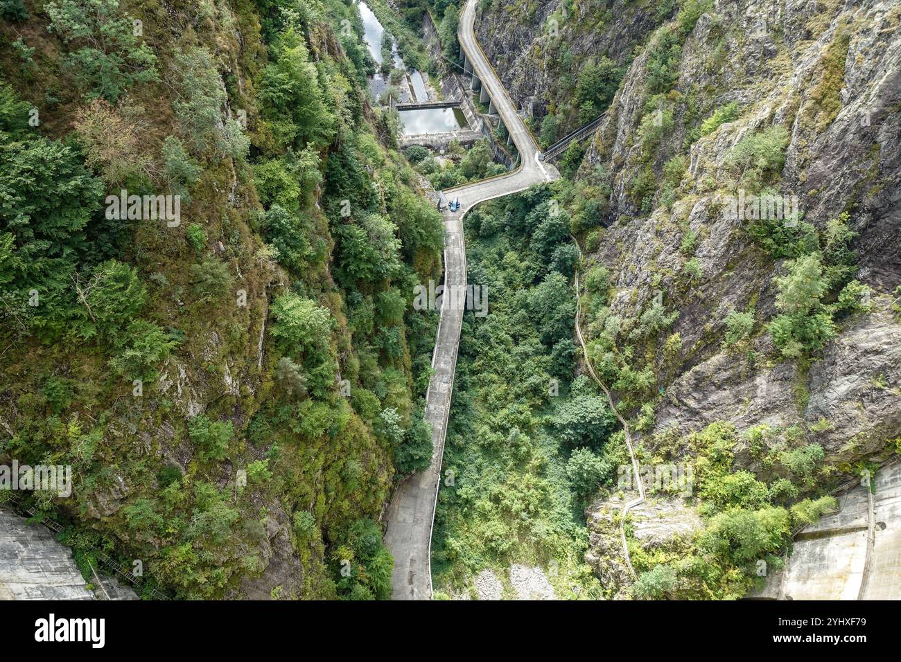 Die sich windende Bergstraße des Staudamms führt durch eine tiefgrüne, bewaldete Schlucht mit steilen Felsklippen auf beiden Seiten, am Vidraru-Staudamm, Transfăgărășan Stockfoto