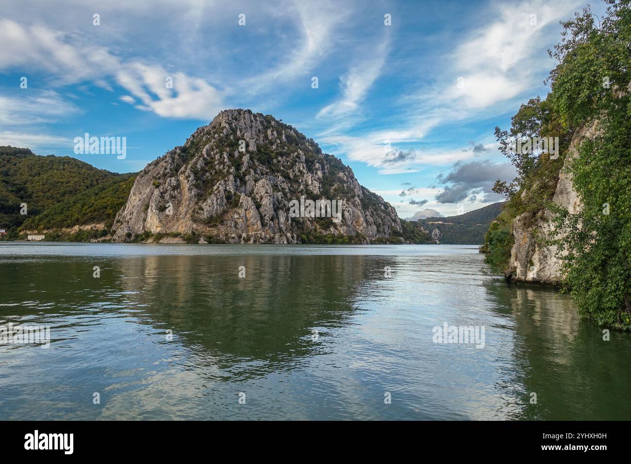Malerischer Blick auf die Eisernen Tore, die Flussufer der Donau, flankiert von steilen Klippen mit einer kleinen Siedlung entlang der Ufer unter teilweise bewölktem Himmel Stockfoto