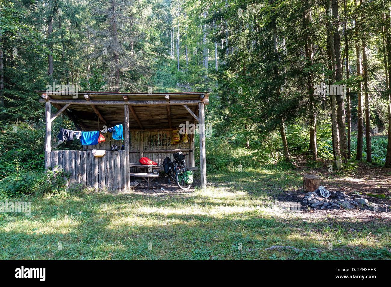Rustikaler Holzunterstand in einer üppigen Waldlichtung mit Wäscherei und Campingausrüstung sichtbar, Niedere Tatra, Slowakei Stockfoto