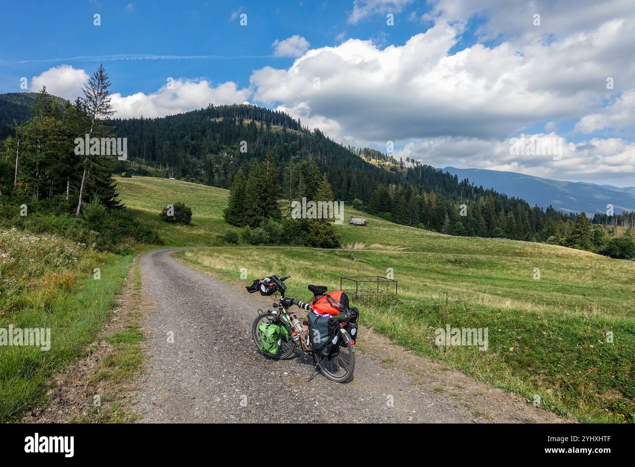 Fahren Sie mit dem Fahrrad auf einer malerischen Schotterstraße, der Podtatranská Magistrala in der Hohen Tatra der Slowakei, vor dem Hintergrund einer üppigen Berglandschaft Stockfoto