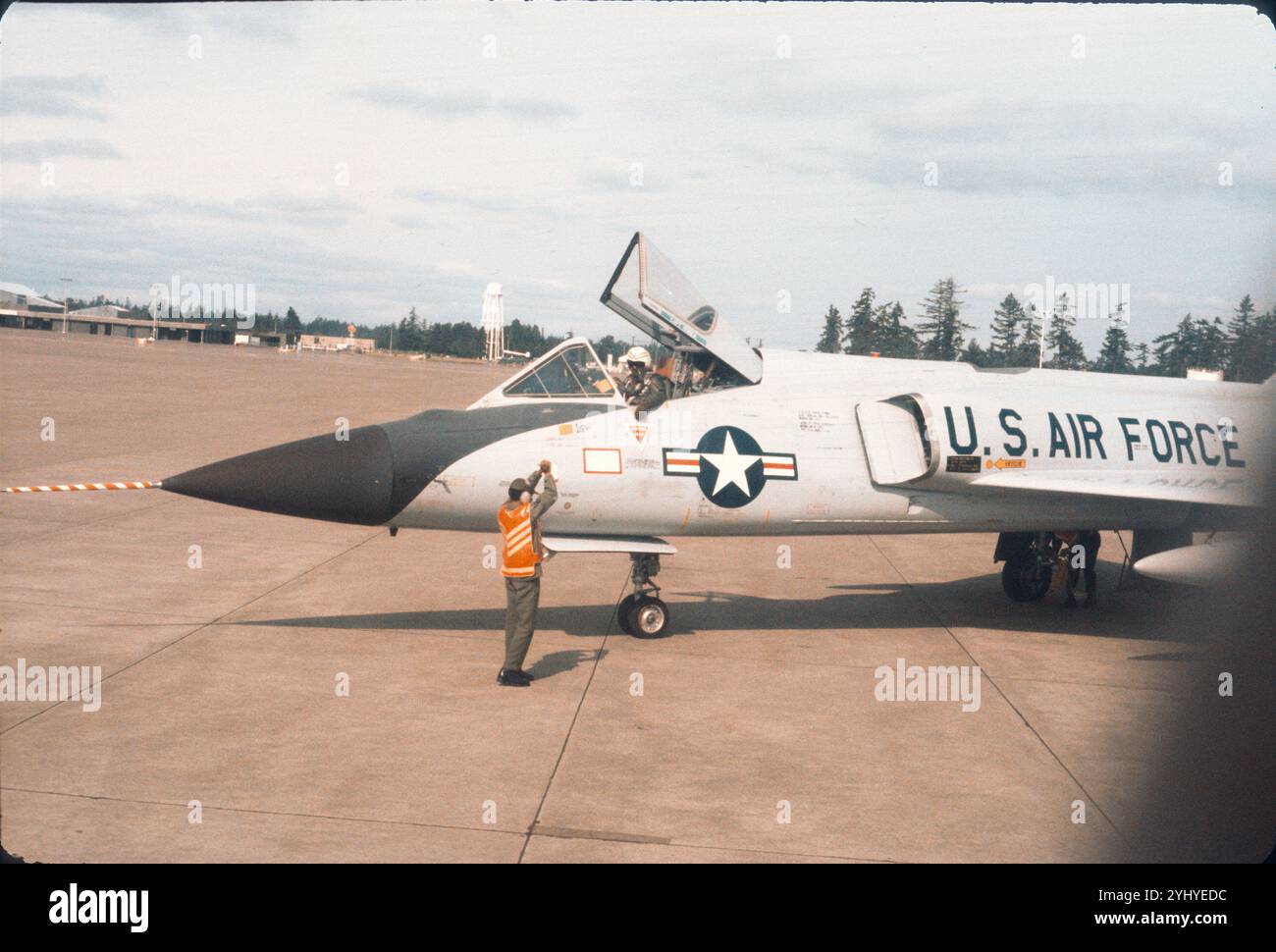 Crewchef gibt Hold-Signal, bevor das 318. FIS F-106A Taxi rausfährt. Stellvertretender Crewchef unter dem Flugzeug, der Keile zieht. McChord AFB, Mai Juni 1975. Stockfoto