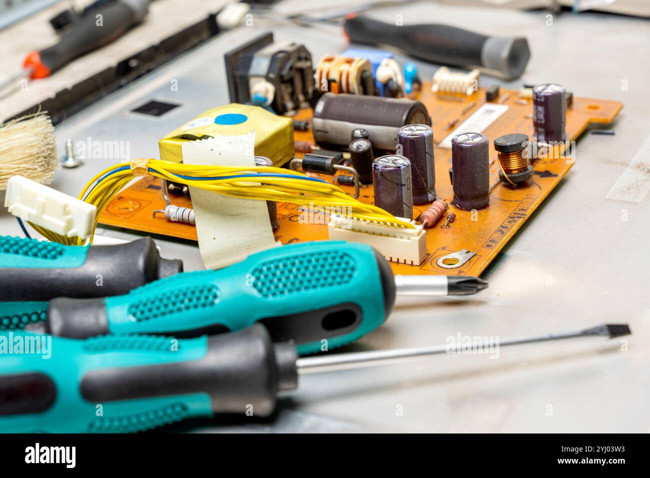 Nahaufnahme von Schraubendrehern und elektronischer Leiterplatte mit Komponenten des Mikrochips, integrierter Schaltungen, Kondensatoren, Widerständen und elektronischer Co Stockfoto