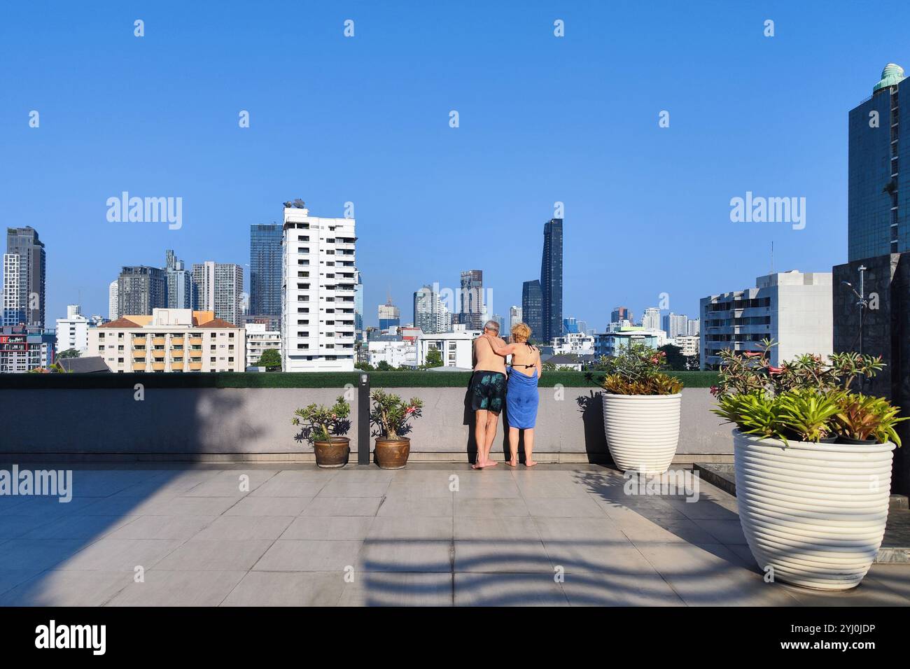 Bangkok, Thailand - 16. Oktober 2024 : ältere ältere ältere Ehepaare stehen am Pool auf dem Dach, mit Blick auf die moderne Skyline der Stadt im Hotel am Sommertag. Stockfoto