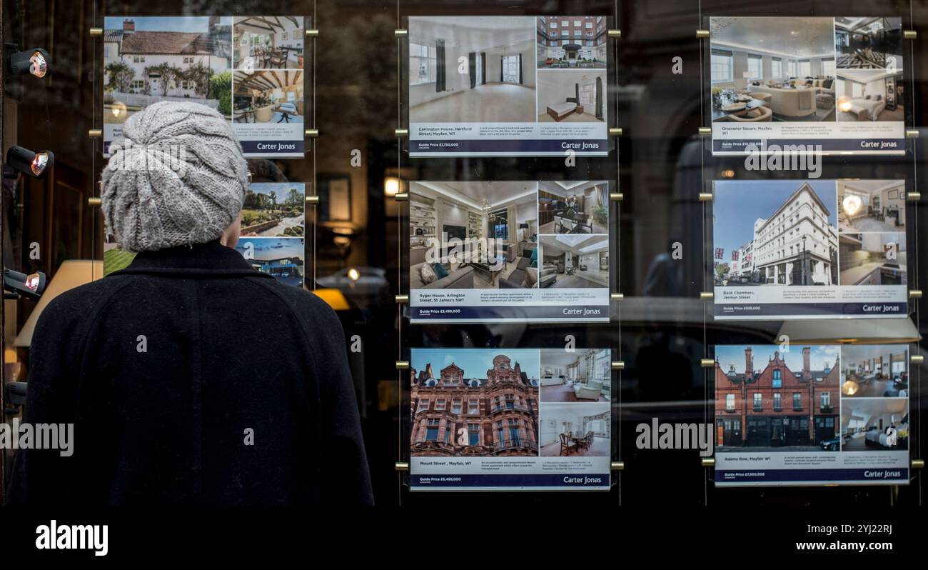 Aktenfoto vom 03/17 eine Frau, die Häuser zum Verkauf im Fenster eines Immobilienmaklers in Mayfair, London, ansieht. Laut Analyse könnten Käufer von Eigenheimen in der Regel mehr als 40.000 £ sparen, wenn sie ein „Fixer-Upper“-Grundstück kaufen. Der durchschnittliche Preis für ein Haus mit Fixer-Upper-Wohnung liegt bei £327.224, was £44.634 unter dem typischen Preis von £371.858 für ein Haus in Großbritannien ist, sagte Rightmove. Erscheinungsdatum: Mittwoch, 13. November 2024. Stockfoto