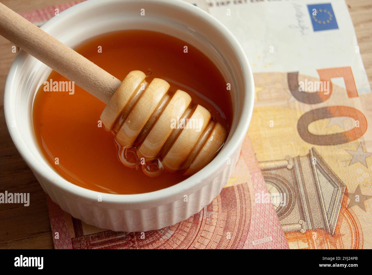 Honigschale mit verstreuten Bienenpollen und Kamille, die natürliche Gesundheit und Süße symbolisiert. Stockfoto