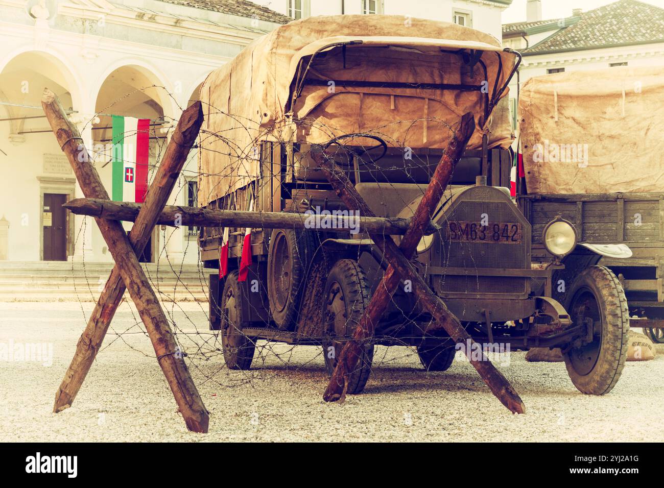 Militärfahrzeuge aus dem 1. Weltkrieg auf einem wunderschönen italienischen Platz. Historische Rekonstruktion einer Kriegsszene mit alten Militärwagen und Cheval de Frise. Stockfoto