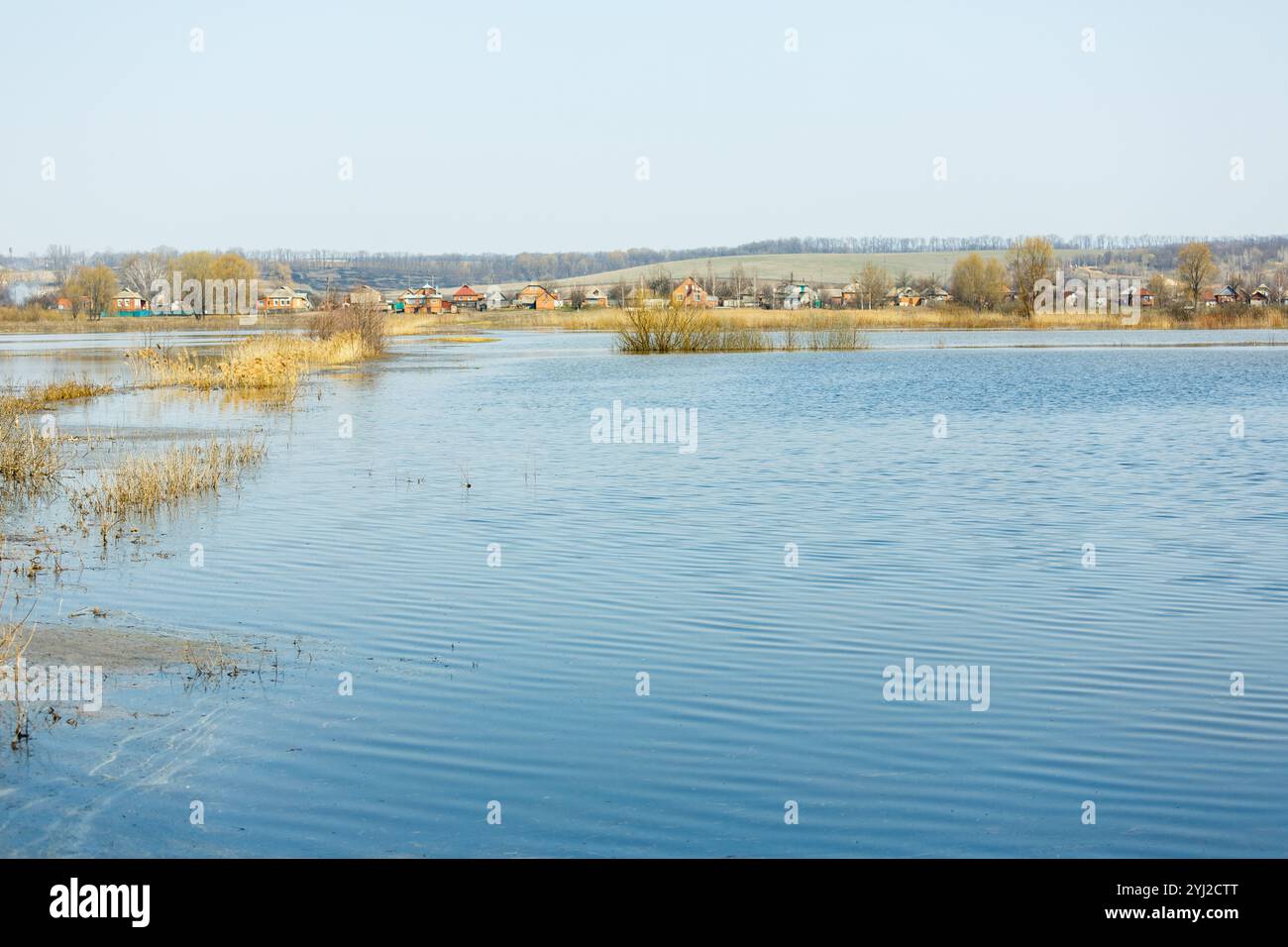 Die Frühlingsflut überflutete das Feld und die Dorfstraße. Hochwasser auf Feldern, auf dem Land. Bäume im Wasser. Klimawandel, globale Erwärmung. Globa Stockfoto