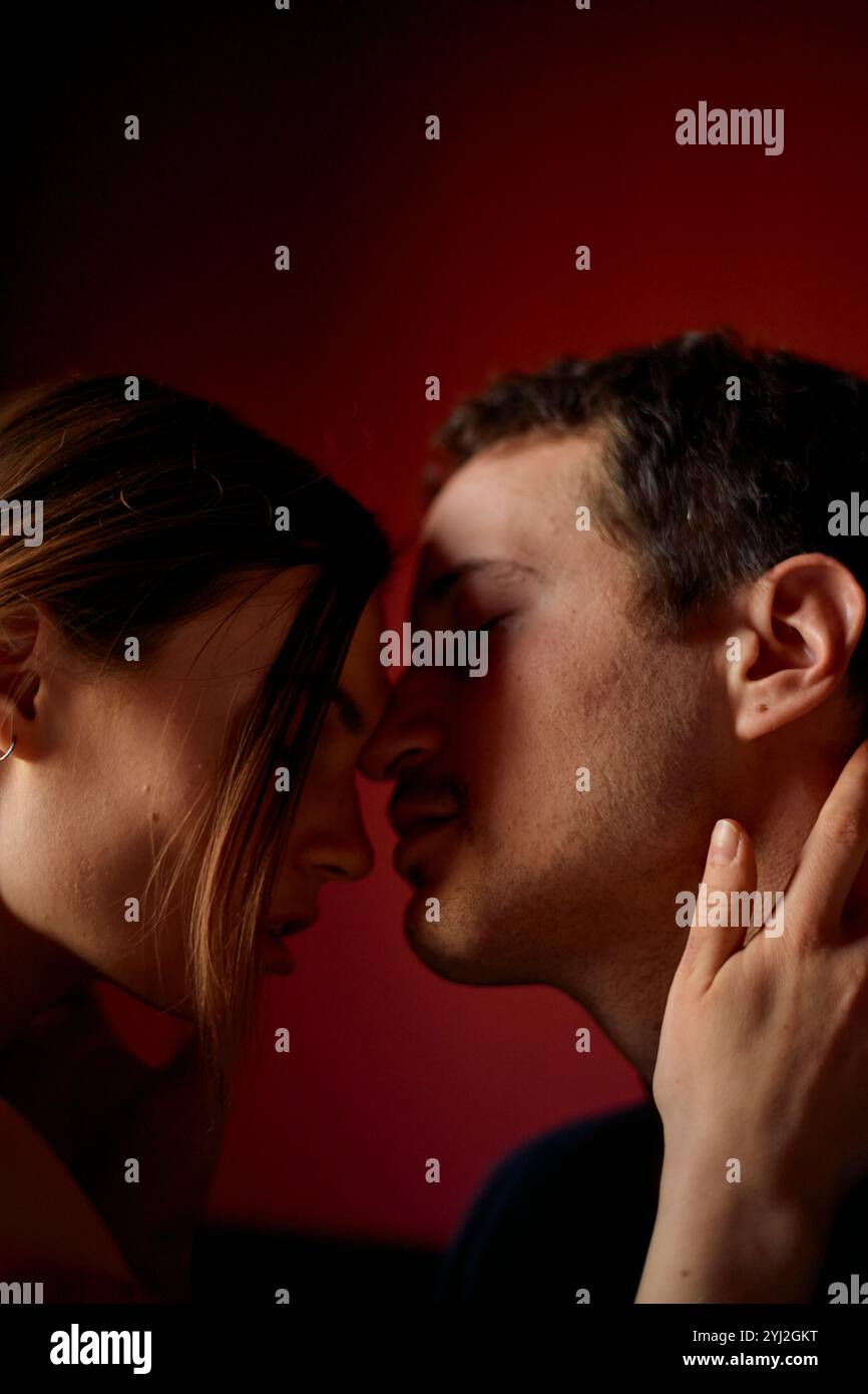 Intimer Moment zwischen einem Paar, während sie sich küssen, beleuchtet durch warme Umgebungsbeleuchtung. Stockfoto