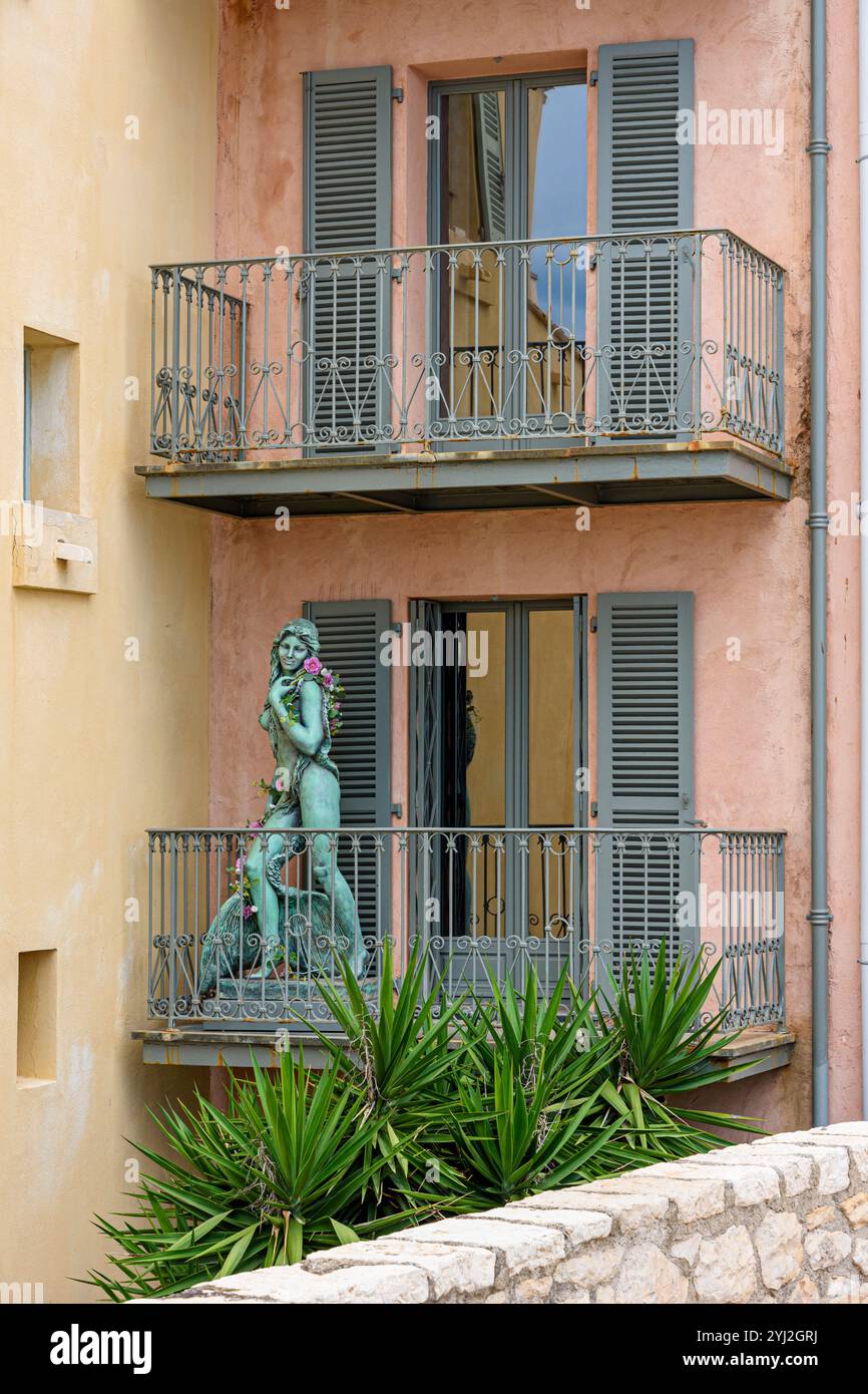 Pastellfarbenes Haus mit einer Skulptur auf dem Balkon in Antibes, Provence-Alpes-Côte d'Azur, Frankreich Stockfoto