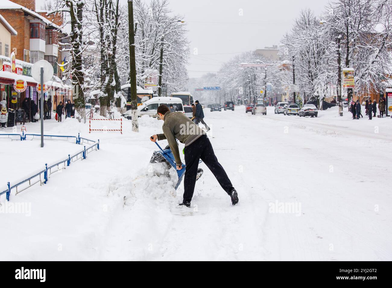 Ukraine, die Stadt Romny, 18. Januar 2018: Ein Mann entfernt an einem verschneiten Wintertag Schnee von den Straßen der Stadt. Städtische Schneeräumung und Menschen Stockfoto