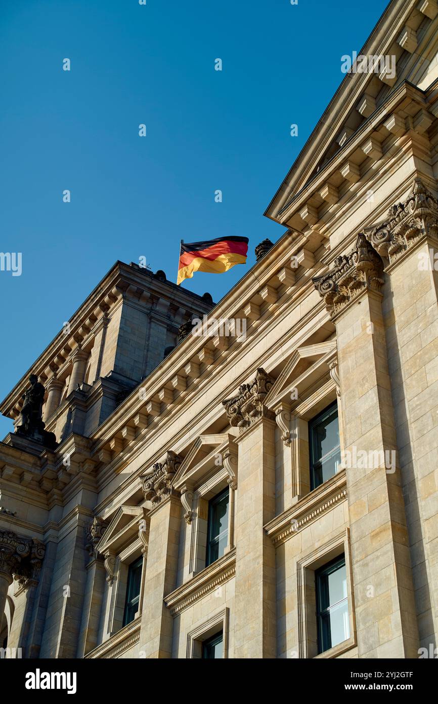 Deutsche Flagge winkt über dem Reichstagsgebäude mit klarem blauem Himmel im Hintergrund, Berlin, Deutschland Stockfoto