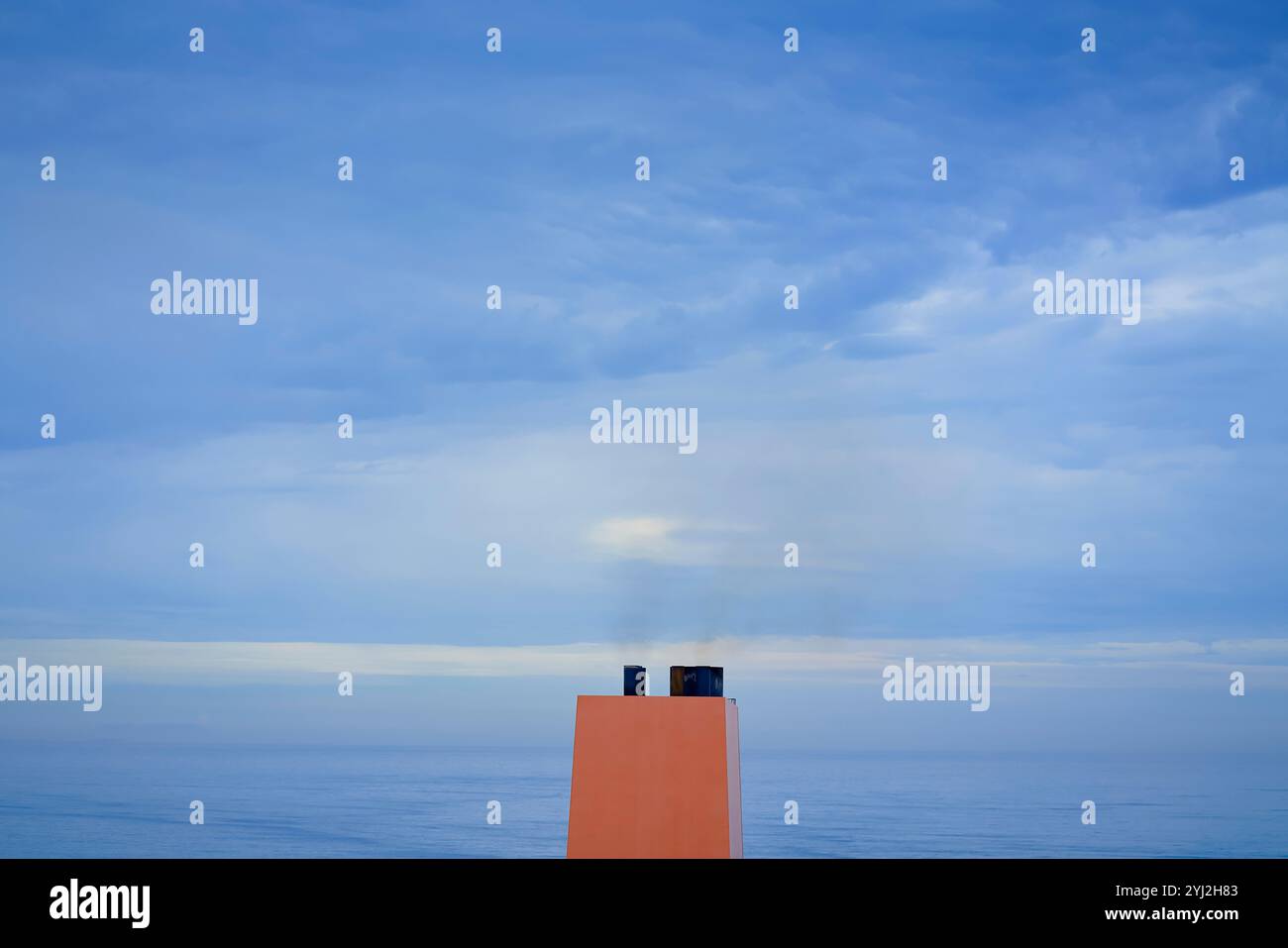 Rauch zieht aus einem Schiffstrichter vor dem Hintergrund eines ruhigen Meeres und bedeckten Himmels, Busan, Korea Stockfoto