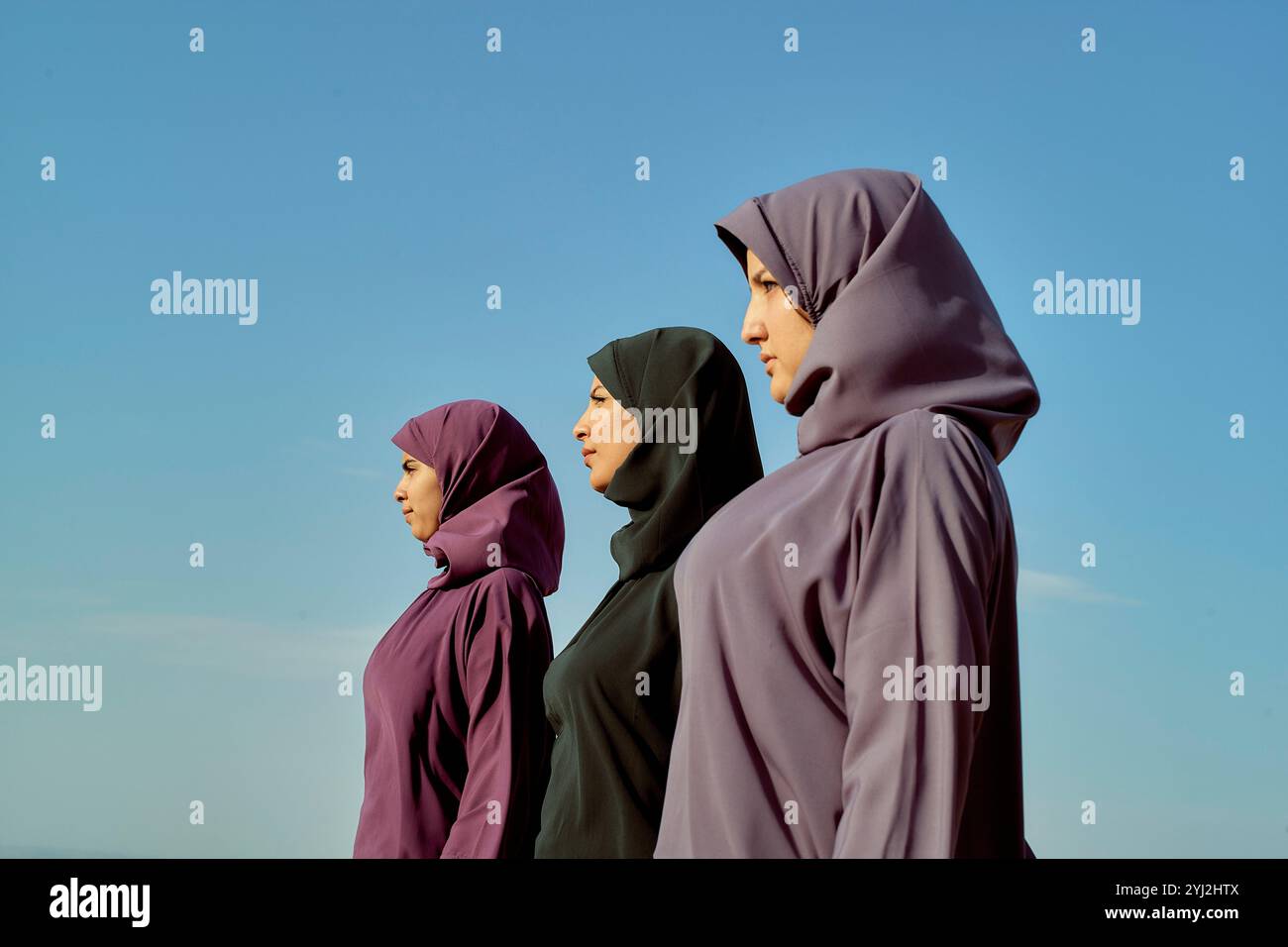 Drei Frauen in Hijabs stehen Seite an Seite vor einem klaren blauen Himmel, Marokko Stockfoto