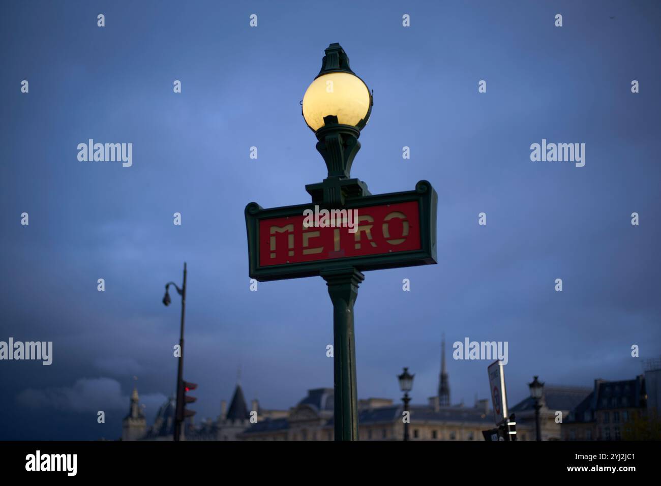 Beleuchtetes Metro-Schild vor einem dunklen Himmel mit Silhouette der Skyline der Stadt im Hintergrund. Stockfoto