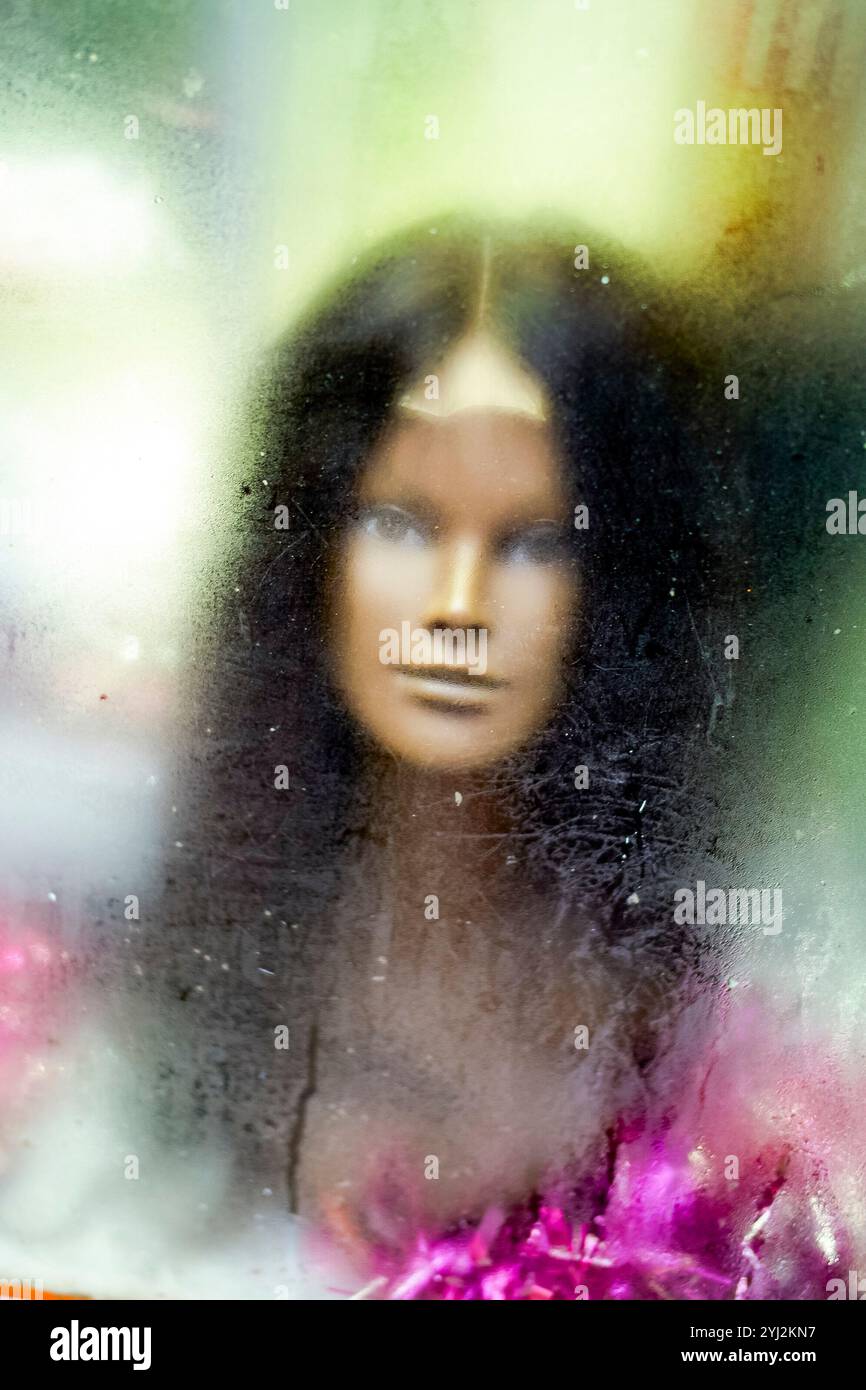 Schauriger weiblicher Marionettenkopf durch das dampfende Fenster einer Ladenausstellung gesehen Stockfoto