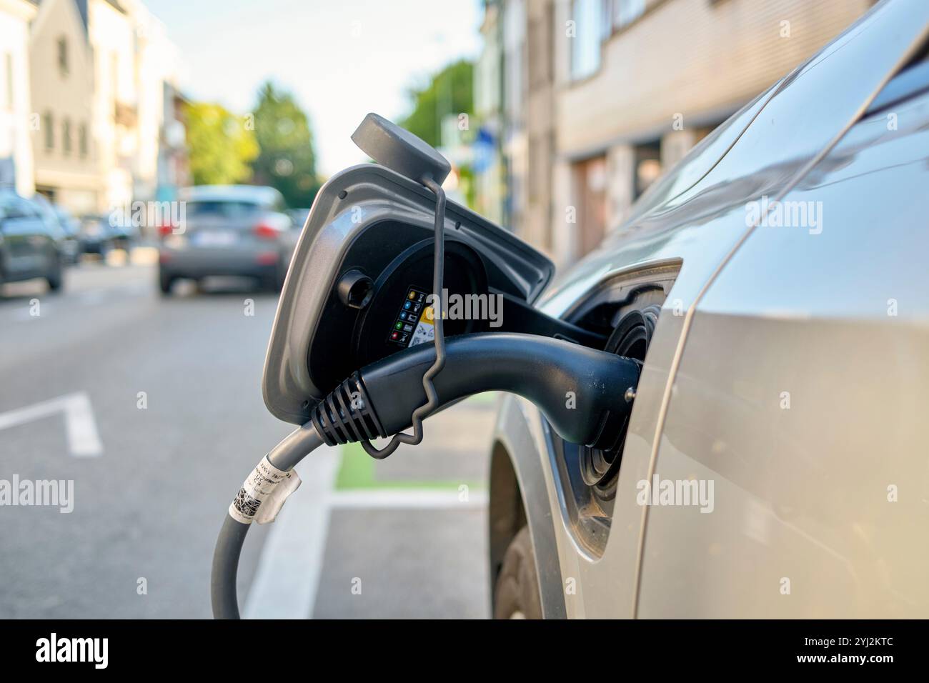 Elektroauto wird tagsüber an einer Straßenladestelle aufgeladen. Stockfoto