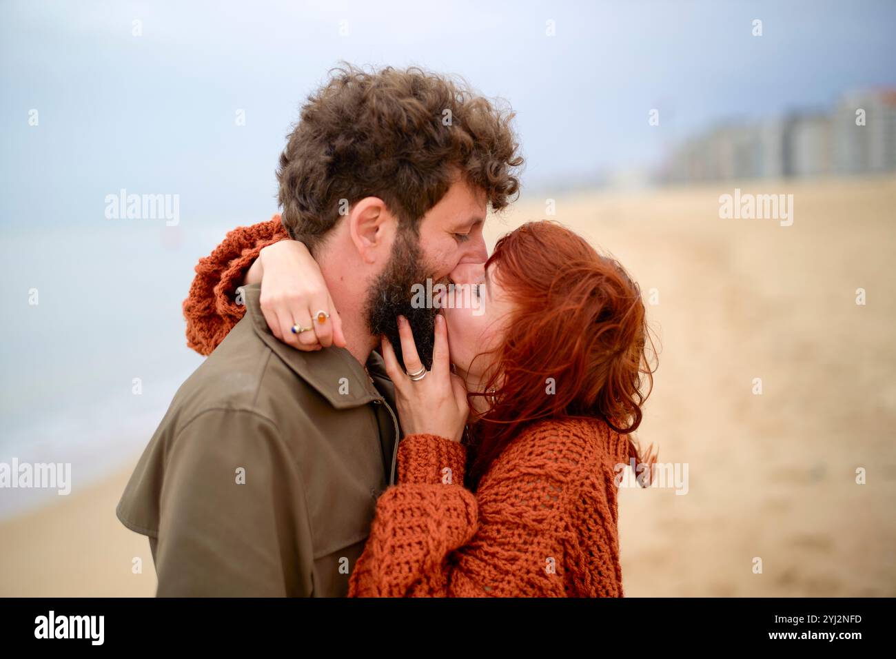 Paare umarmen und küssen sich an einem Sandstrand mit bewölktem Himmel im Hintergrund, Belgien Stockfoto