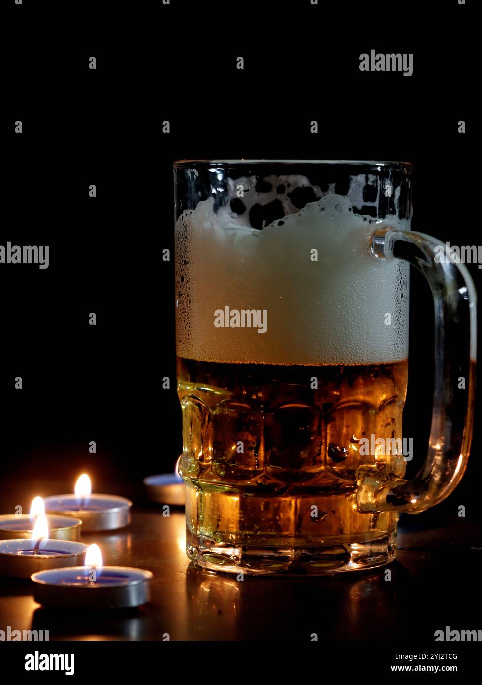 Eine konzeptionelle Tischfotografie mit Bierglas und Kerzenlichtern. Stockfoto