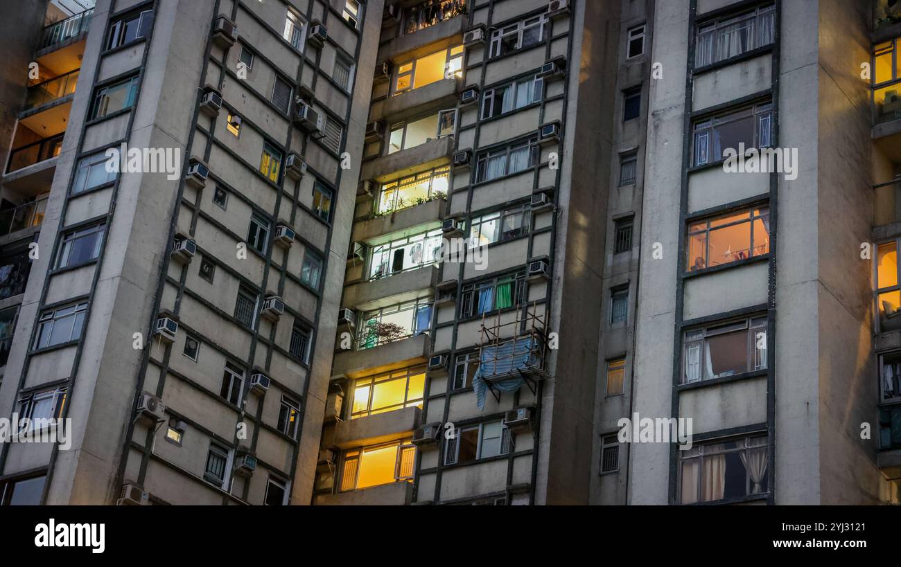 Fenster von Wohngebäuden beleuchten den Abend, wenn die Sonne über Hongkong untergeht, und heben das urbane Leben und die Architektur hervor. Stockfoto