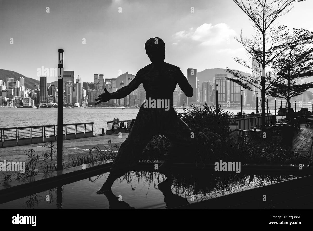 Die Bruce Lee Statue ist an der Uferpromenade sichtbar und zeigt die berühmte Figur vor der Skyline von Hongkong. Stockfoto