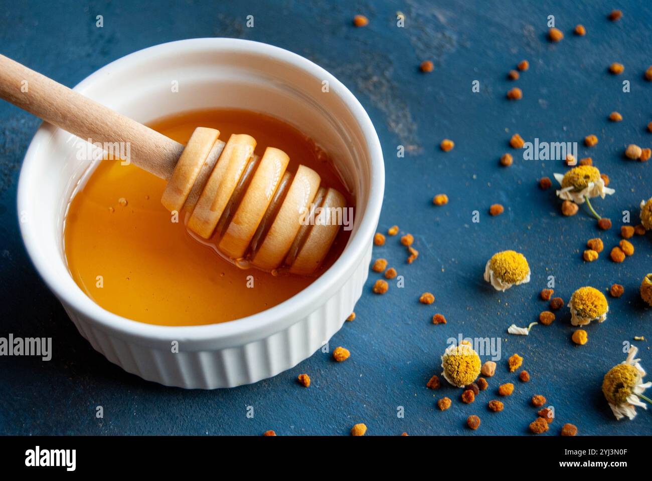 Bio-Honig mit Kamillenblüten und Bienenpollen für eine natürliche und erdige Komposition. Stockfoto