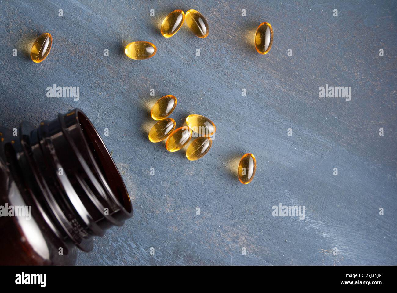 Omega-3 Fischöl Kapseln und Flaschen verstreut auf blauem Hintergrund, die Gesundheit und Wellness hervorheben. Stockfoto