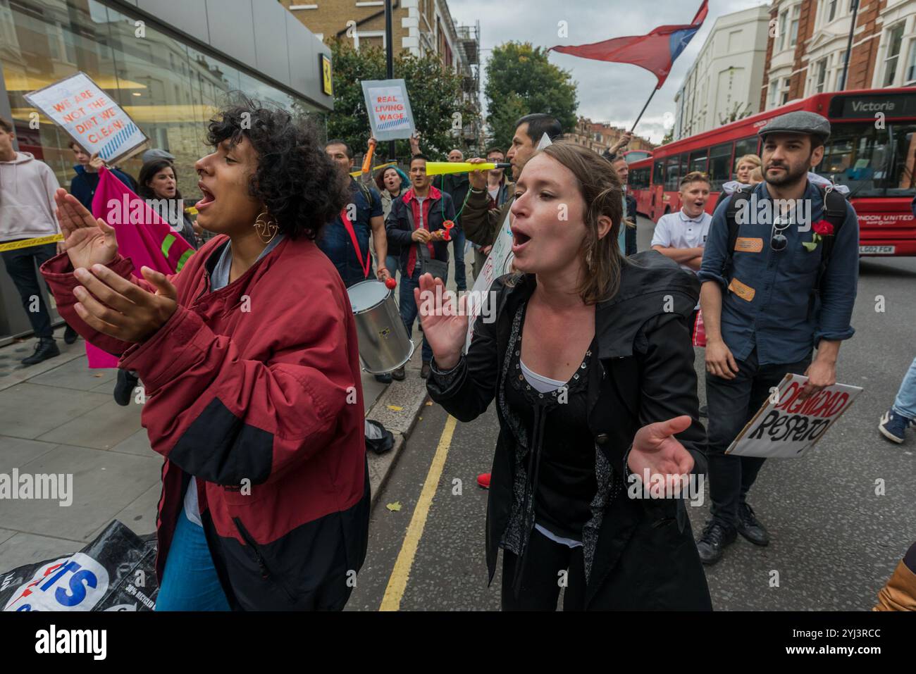 London, Großbritannien. 30. September 2017. Demonstranten tanzen vor dem Ferrari-Showroom des Kensington-Luxuswagenhändlers HR Owen bei den United Voices of the World Trade union Protest, dass sie ihre beiden Putzfrauen wieder einsetzen, die ohne Bezahlung ausgesetzt wurden, weil sie darum baten, für die Reinigung der Ferrari/Maserati Showrooms einen Lebenshaltungslohn in London zu erhalten. Die Putzer Angelica Valencia und Freddy Lopez wurden von der UVW und anderen Gruppen wie Class war und der RCG unterstützt. Etwa hundert Demonstranten marschierten von der South Kensington Station aus und protestierten kurz vor den Lamborghini Showrooms und dem Büro Stockfoto