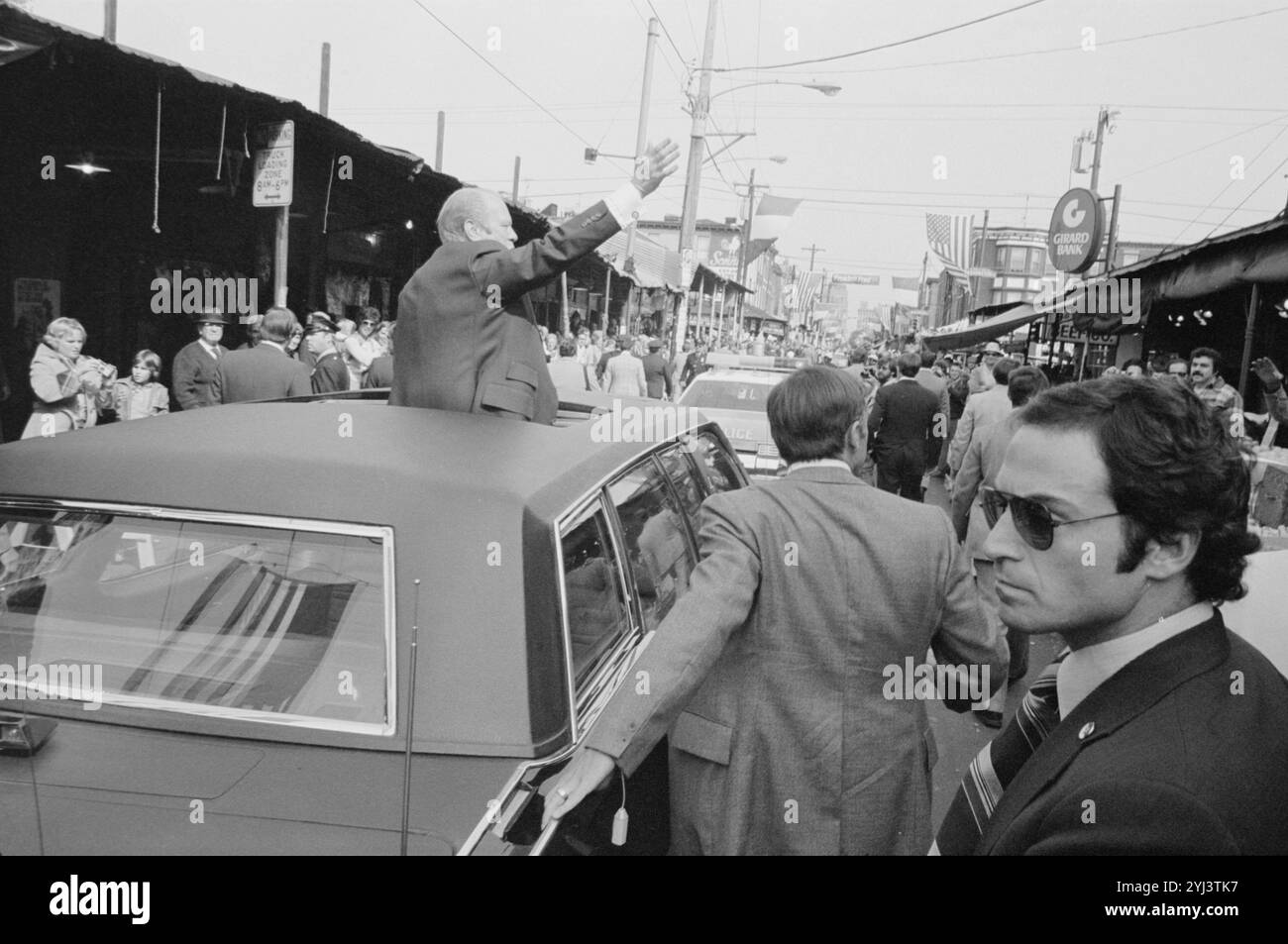 Präsident Gerald Ford, umgeben von Sicherheitspersonal, winkt vom Sonnendach eines Autos in Philadelphia, Pennsylvania. USA. September 1976 Stockfoto