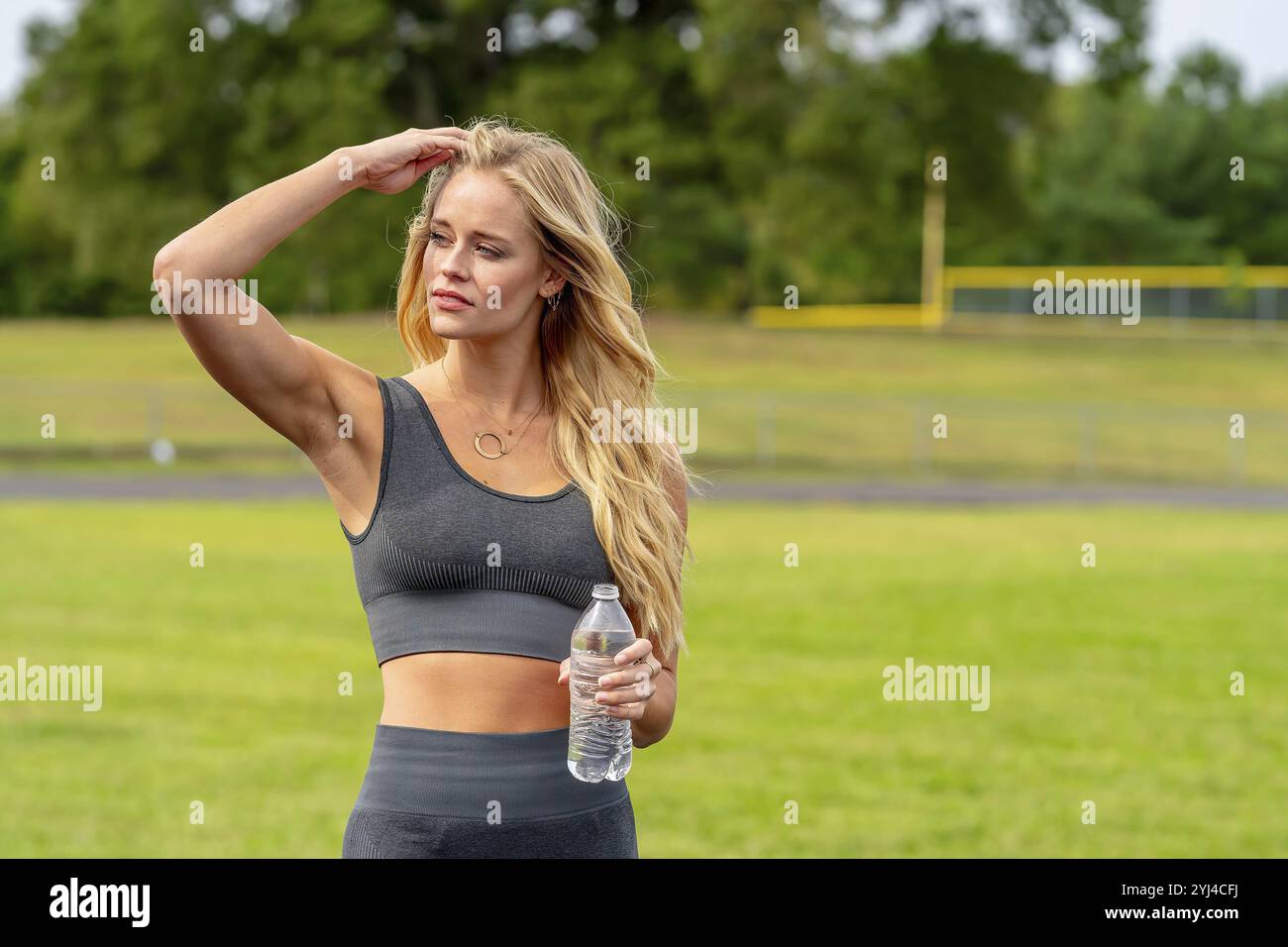 Ein atemberaubendes, blondes Fitnessmodell bereitet sich auf ein Workout vor, das Selbstvertrauen und Entschlossenheit bei jeder Bewegung ausstrahlt Stockfoto