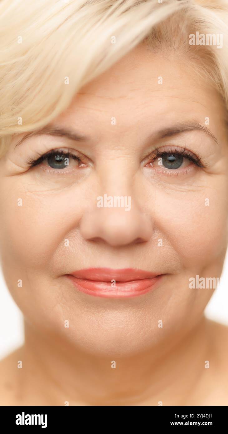 Frontale Aufnahme des Gesichts der Frau, die ihre blauen Augen mit langen Wimpern vor weißem Studiohintergrund hervorhebt. Gepflegte, glänzende Haut. Stockfoto