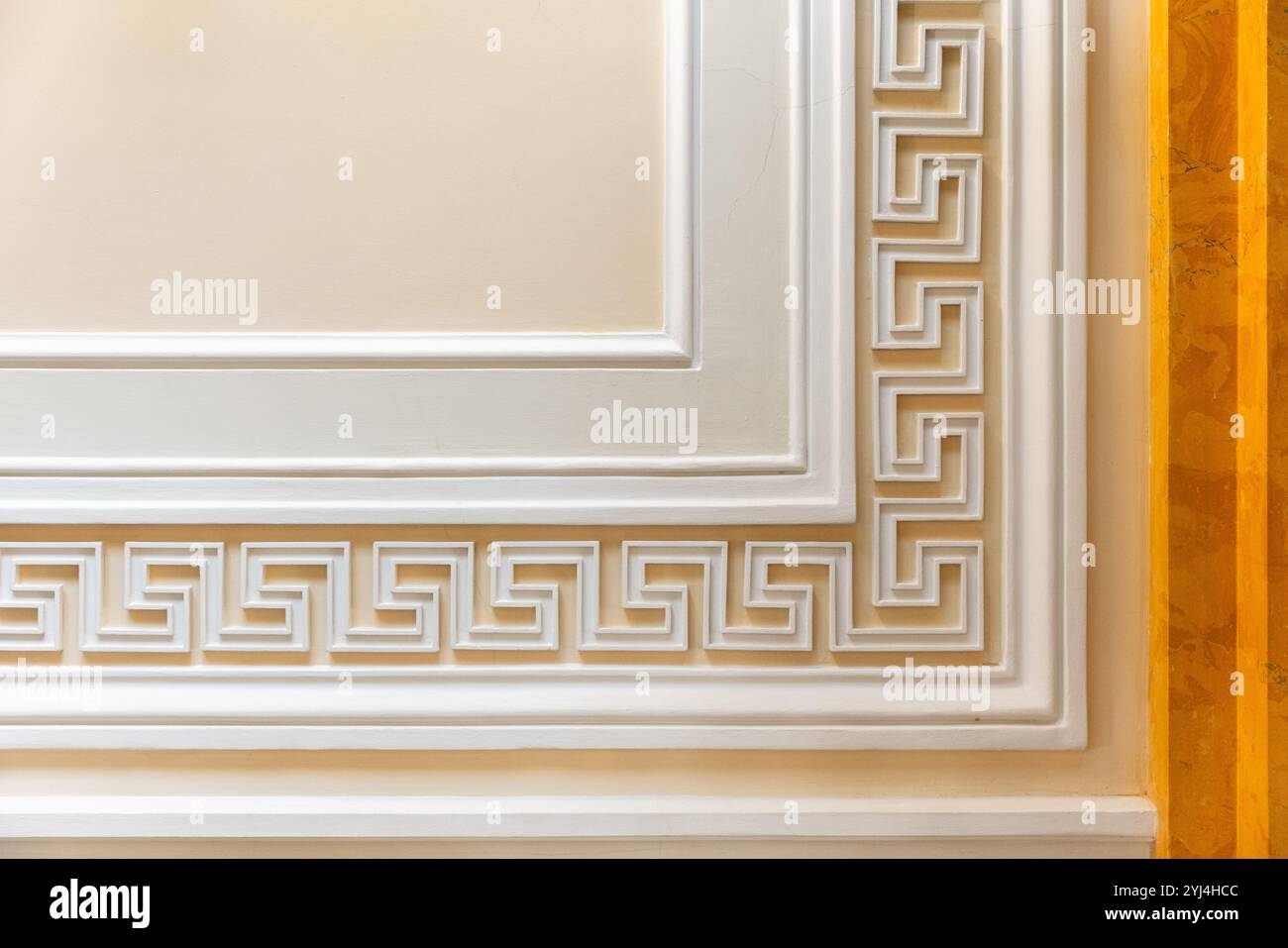 Dekorative Wandelemente mit weißem Meander-Motiv über gelbem Hintergrund, klassische antike Architekturvorlage, Hintergrundfotostruktur Stockfoto