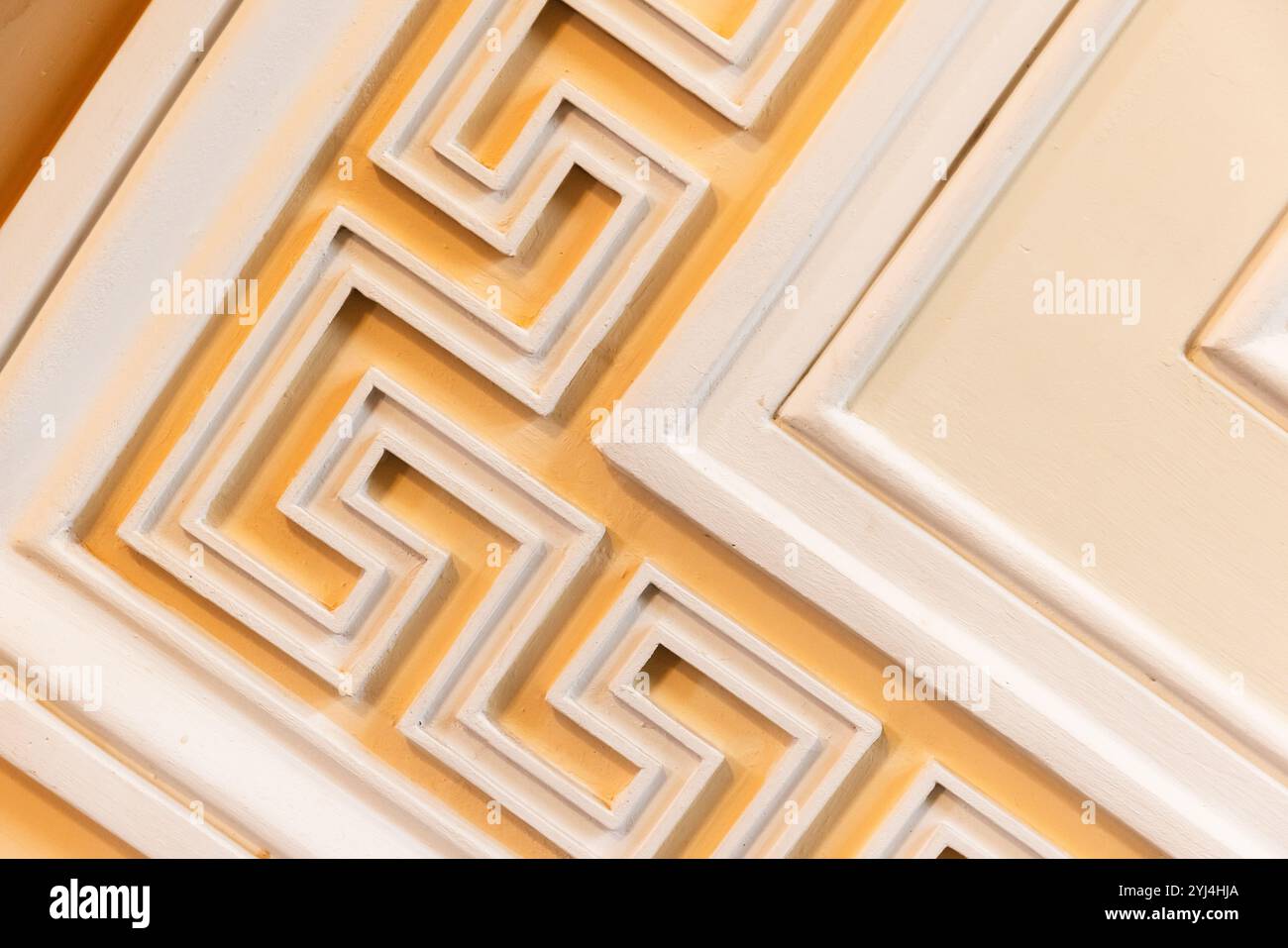 Klassische Wandelemente mit weißem Meander-Motiv über gelbem Hintergrund, antike Architekturvorlage, Hintergrundfotostruktur Stockfoto