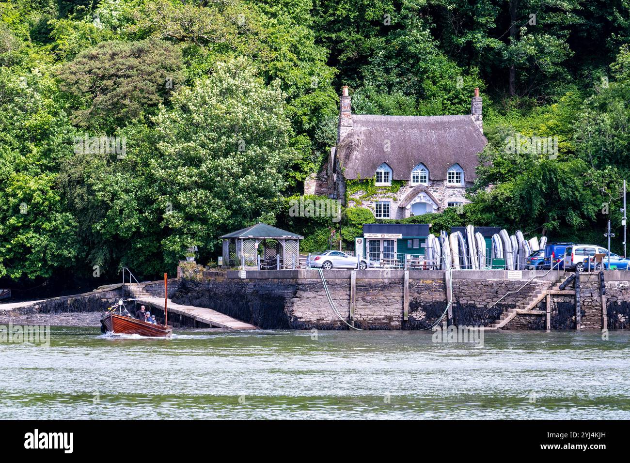 Detail der Passagierfähre, die Greenway Quay nach Dittisham am River Dart verlässt, mit Cottage und Dingy Rack. Stockfoto Detail der Passagierfähre, die Greenway Quay nach Dittisham am River Dart verlässt, mit Cottage und Dingy Rack. Stockfoto