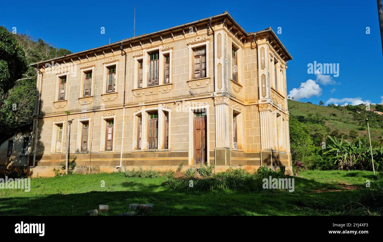 Ein großes, verwittertes Kolonialhaus steht stolz vor der Kulisse sanfter Hügel und üppiger Grünflächen. Stockfoto
