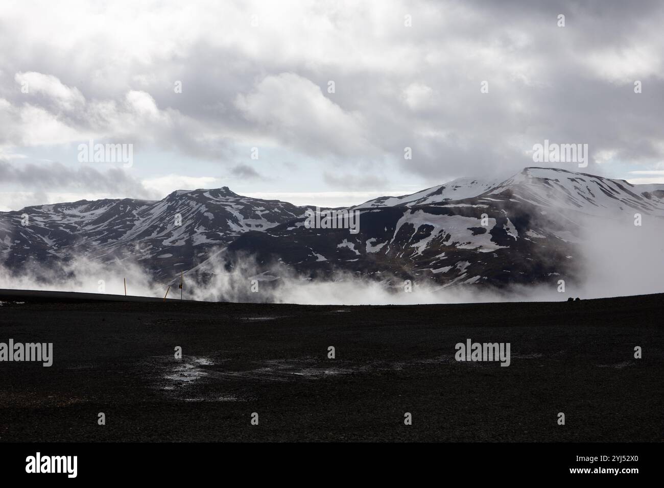 Schneebedeckte vulkanische Dyrfjoll-Gebirgskette, Gipfel über den niedrigen Wolken und Nebel in Storurd Area in Ost-Island. Stockfoto